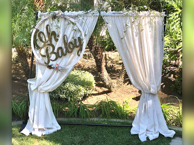 Oh baby sign displayed on the top left corner of a backdrop display with linen curtain decorations.